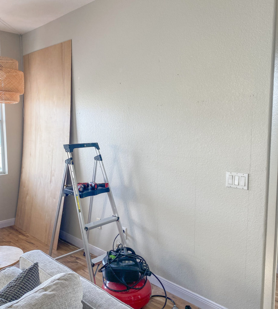 Board and Batten Wall by popular San Diego DIY blog, Domestic Blonde: image of a grey wall a step ladder, some plywood boards, and a a sander. 