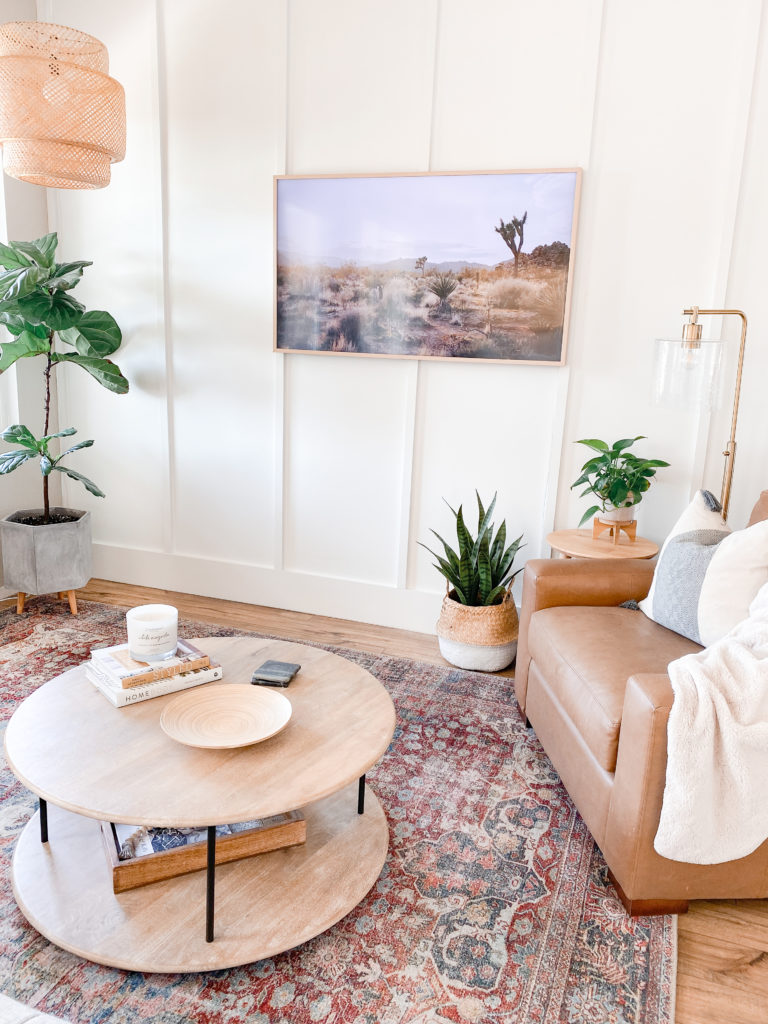 Board and Batten Wall by popular San Diego DIY blog, Domestic Blonde: image of a room with a white board and batten wall, a camel brown leather arm chair, a round wooden coffee table, a fiddle leaf fig tree, and a framed picture of some Joshua Trees. 