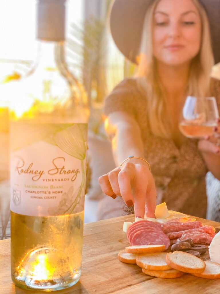 Rodney Strong Wines by popular San Diego lifestyle blog, Domestic Blonde: image of a woman holding a glass of Rodney Strong wine and eating from a charcuterie board. 