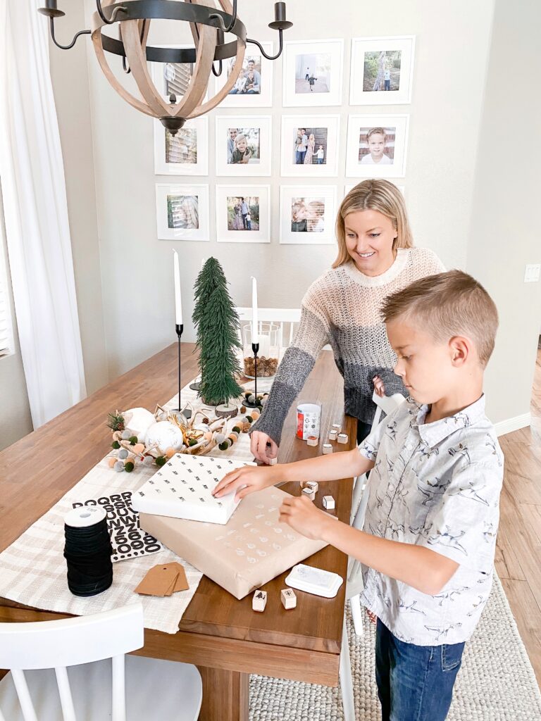 Personalized Wrapping Paper by popular San Diego DIY blog, Domestic Blonde: image of a boy and his mom stamping wrapped presents with pine tree stamps.