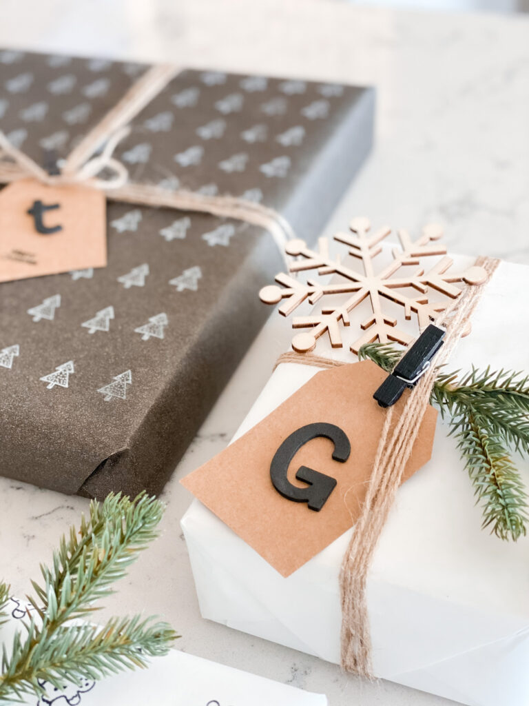Personalized Wrapping Paper by popular San Diego DIY blog, Domestic Blonde: image of personalized presents wrapped in twine and embellished with a pine twig, wooden snowflake, and monogram gift tag. 