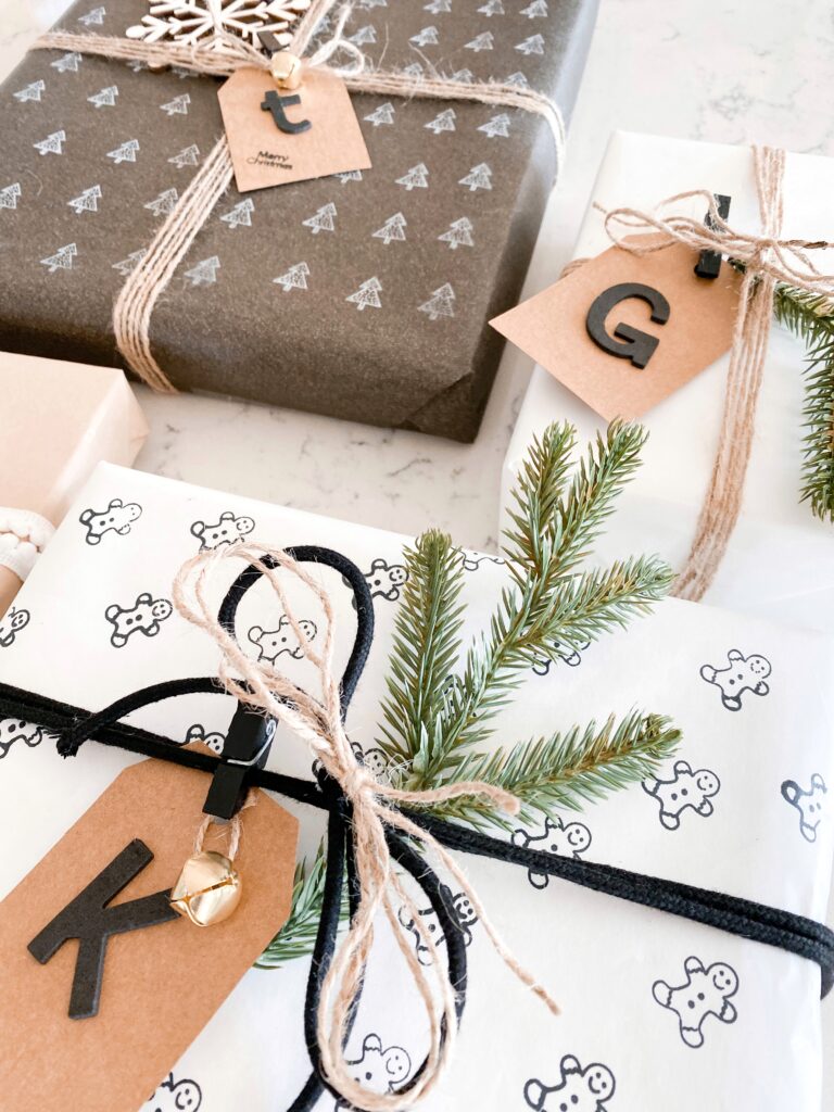 Personalized Wrapping Paper by popular San Diego DIY blog, Domestic Blonde: image of personalized presents wrapped in twine and embellished with a pine twig, wooden snowflake, and monogram gift tag. 